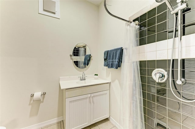 bathroom featuring baseboards, tile patterned floors, tiled shower, and vanity