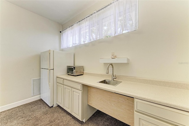 kitchen with light carpet, a sink, freestanding refrigerator, a toaster, and visible vents