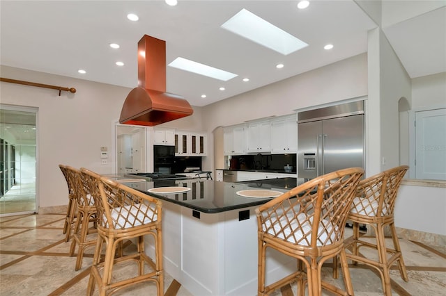 4307 Camino Real, Sarasota, FL 34231 - kitchen featuring inlaid floor details, stainless steel built in refrigerator, dark countertops, a skylight, and white cabinets