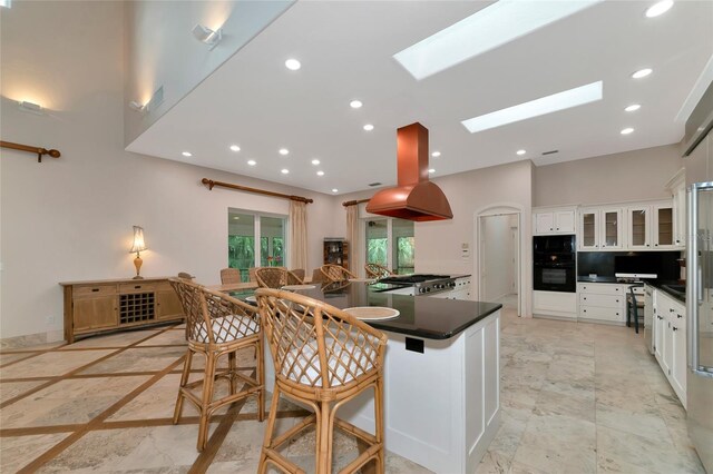 4307 Camino Real, Sarasota, FL 34231 - kitchen with island exhaust hood, black appliances, dark countertops, white cabinets, and a skylight
