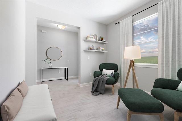 living area with baseboards, plenty of natural light, and light wood-style flooring
