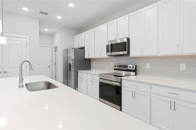 kitchen featuring visible vents, appliances with stainless steel finishes, a sink, light countertops, and white cabinetry