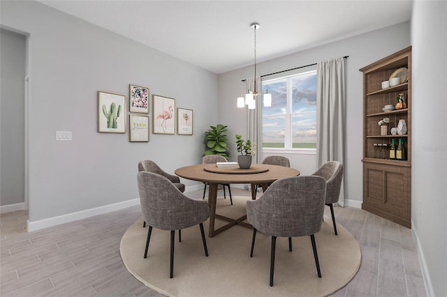dining area featuring baseboards, light wood-type flooring, and an inviting chandelier