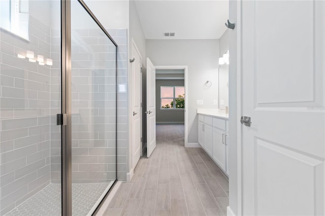 full bathroom with visible vents, a stall shower, wood finished floors, vanity, and baseboards