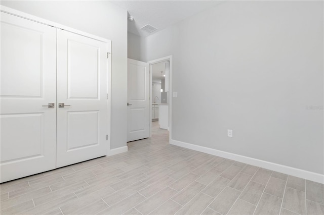 unfurnished bedroom featuring baseboards, visible vents, light wood finished floors, and a closet