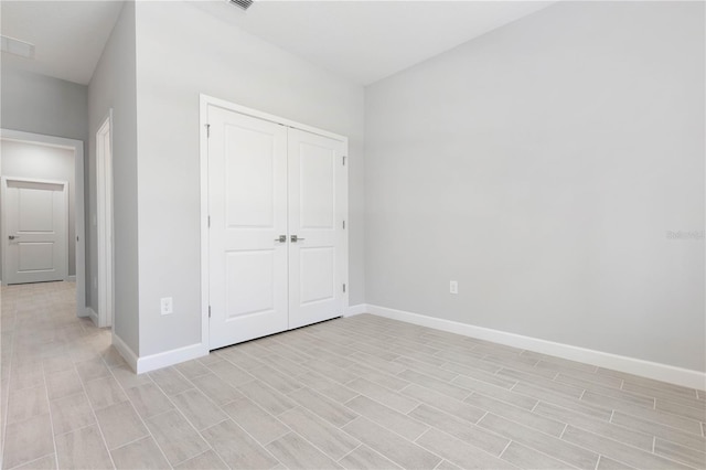 unfurnished bedroom featuring baseboards, light wood-style flooring, and a closet