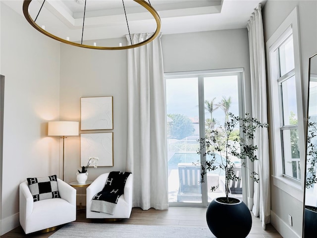 living area featuring heating unit, a wealth of natural light, a raised ceiling, and wood finished floors