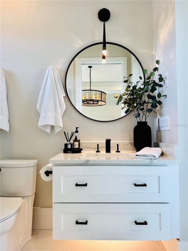half bathroom featuring vanity, marble finish floor, and toilet
