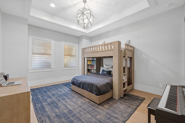 bedroom with an inviting chandelier, recessed lighting, baseboards, wood finished floors, and a tray ceiling
