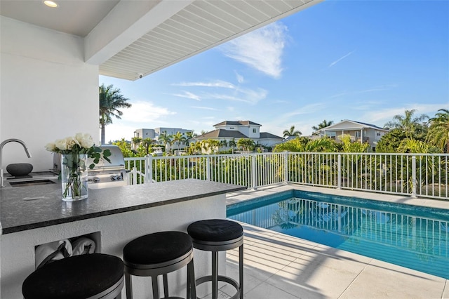 view of pool featuring fence, a grill, an outdoor kitchen, a fenced in pool, and outdoor wet bar