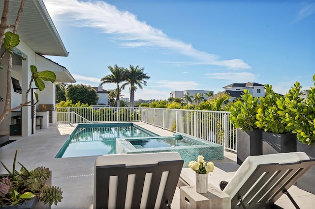 view of swimming pool featuring a fenced backyard, a pool with connected hot tub, a patio area, and an outdoor kitchen