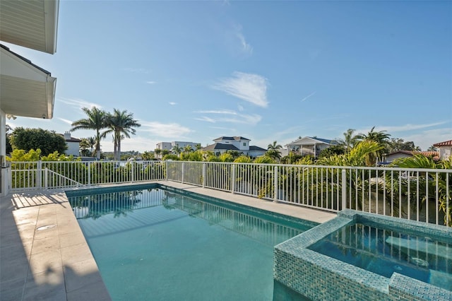 view of pool with fence, a pool with connected hot tub, and a residential view