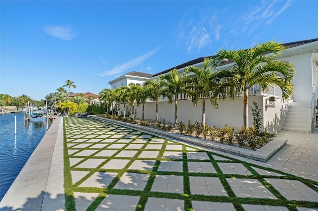exterior space with fence, boat lift, a boat dock, stairs, and a water view