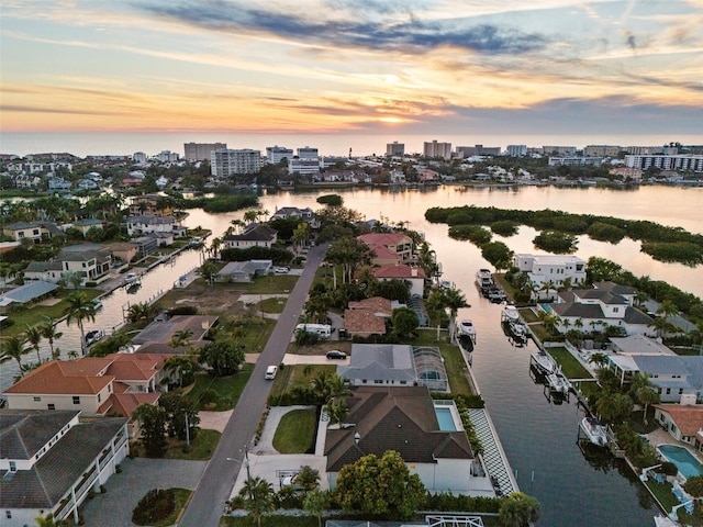 aerial view at dusk with a water view, a residential view, and a view of city