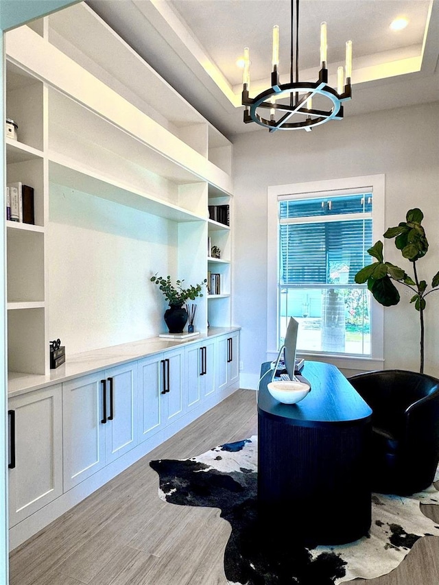 office space with an inviting chandelier, recessed lighting, light wood finished floors, and a tray ceiling