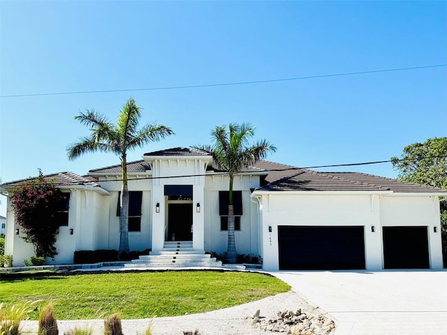 view of front of property with an attached garage, a tile roof, stucco siding, a front yard, and driveway