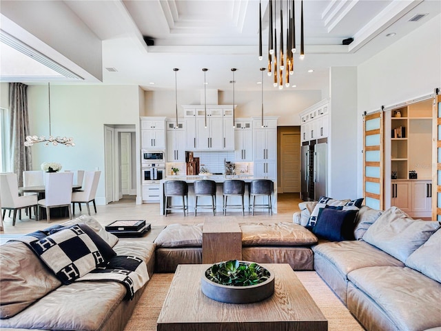 1643 Stanford Ln, Sarasota, FL 34231 - living area featuring a barn door, light wood-type flooring, a high ceiling, recessed lighting, and a raised ceiling