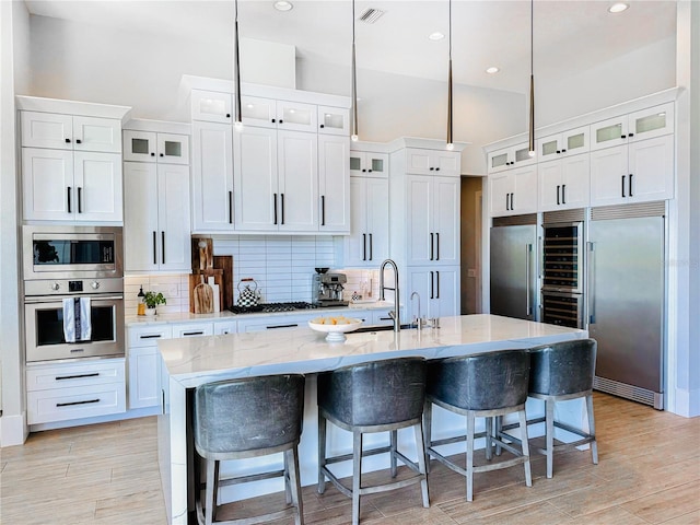 1643 Stanford Ln, Sarasota, FL 34231 - kitchen featuring appliances with stainless steel finishes, backsplash, white cabinetry, a breakfast bar area, and recessed lighting