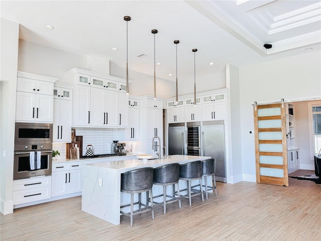 1643 Stanford Ln, Sarasota, FL 34231 - kitchen with appliances with stainless steel finishes, tasteful backsplash, a center island with sink, a breakfast bar, and light wood-style flooring