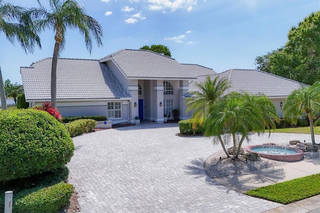 view of front of home featuring an in ground hot tub, stucco siding, driveway, and a tile roof