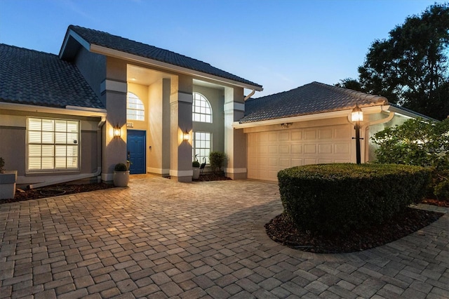 view of front of home with an attached garage, decorative driveway, and stucco siding