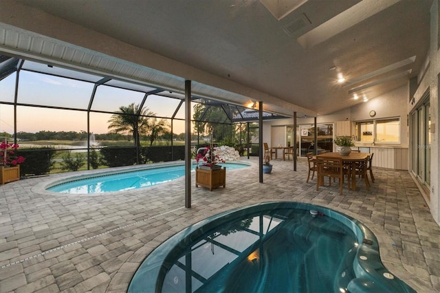 pool at dusk featuring an outdoor pool, a patio area, a jacuzzi, glass enclosure, and outdoor dining space