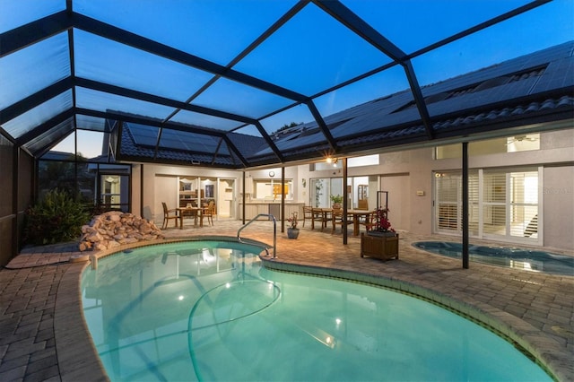 outdoor pool featuring outdoor dining area, glass enclosure, and a patio area