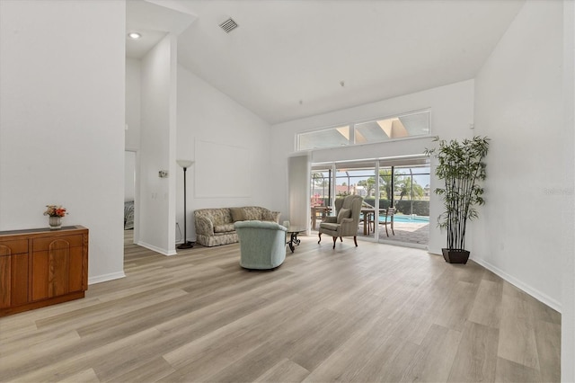 sitting room featuring high vaulted ceiling, baseboards, light wood finished floors, and visible vents
