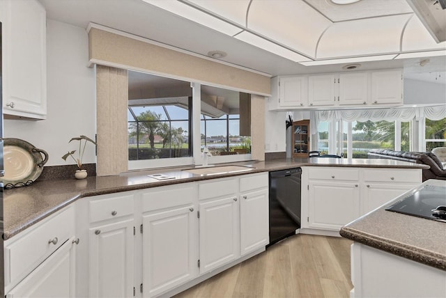 kitchen with dark countertops, white cabinetry, a sink, light wood finished floors, and black appliances