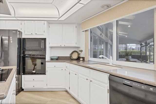 kitchen featuring a sink, light countertops, black appliances, light wood finished floors, and white cabinetry