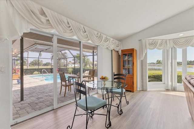 dining area with baseboards, light wood finished floors, a sunroom, and lofted ceiling