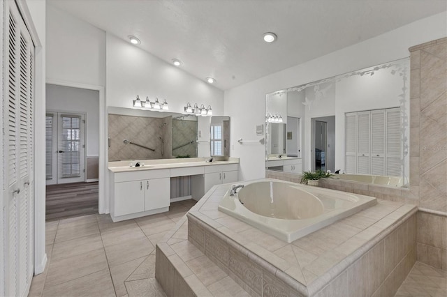 full bathroom with a closet, a bath, a wealth of natural light, and vaulted ceiling