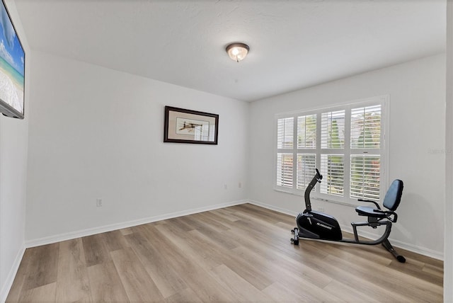 workout area featuring baseboards and light wood-style floors