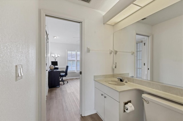 bathroom with visible vents, wood finished floors, vanity, baseboards, and toilet
