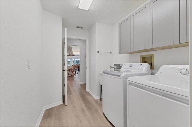 laundry room with visible vents, light wood-style floors, baseboards, washing machine and clothes dryer, and cabinet space