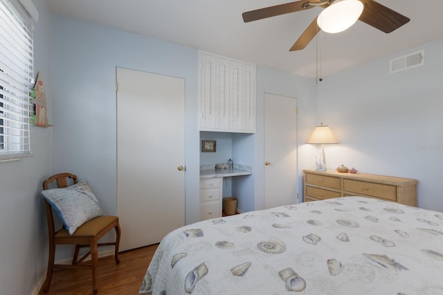 2723 59th St, Sarasota, FL 34243 - bedroom with ceiling fan, built in desk, wood finished floors, and visible vents