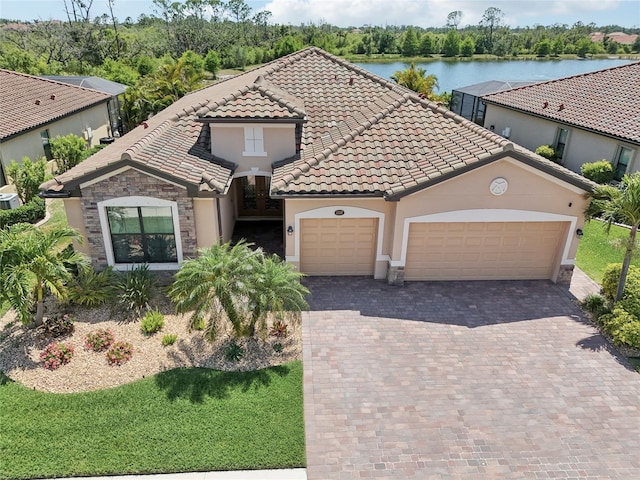 13587 Vancanza Dr, Venice, FL 34293 - mediterranean / spanish house with a garage, decorative driveway, stucco siding, a water view, and a tile roof