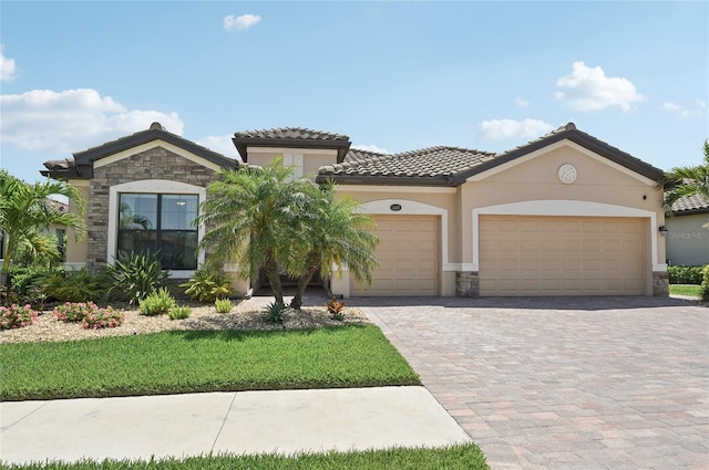 13587 Vancanza Dr, Venice, FL 34293 - mediterranean / spanish-style home with a tiled roof, a garage, decorative driveway, stone siding, and stucco siding
