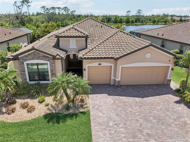 13587 Vancanza Dr, Venice, FL 34293 - mediterranean / spanish house with a tile roof, decorative driveway, a water view, an attached garage, and stucco siding