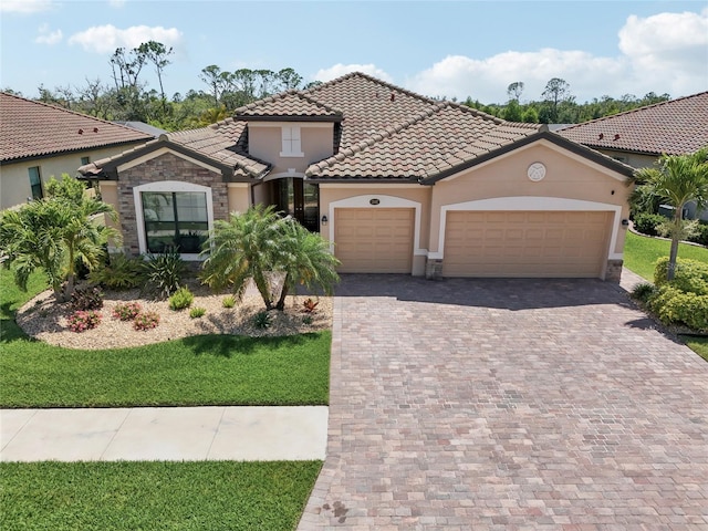 13587 Vancanza Dr, Venice, FL 34293 - mediterranean / spanish-style home with driveway, a tile roof, a garage, stone siding, and stucco siding