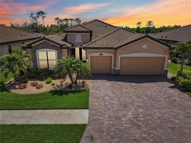 13587 Vancanza Dr, Venice, FL 34293 - mediterranean / spanish-style home featuring a front yard, stucco siding, an attached garage, driveway, and a tile roof