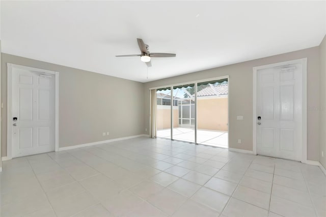 empty room featuring baseboards, a ceiling fan, and light tile patterned floors
