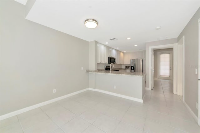 kitchen featuring stainless steel appliances, baseboards, a sink, and a peninsula
