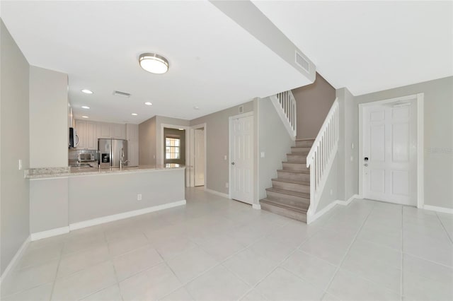 unfurnished living room featuring baseboards, stairs, light tile patterned floors, and visible vents