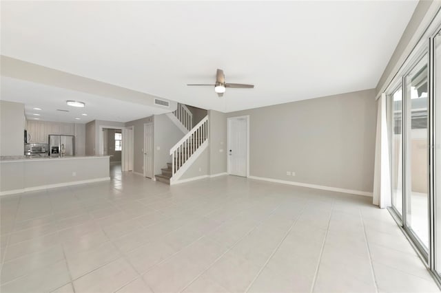 unfurnished living room featuring light tile patterned flooring, stairs, a ceiling fan, baseboards, and visible vents