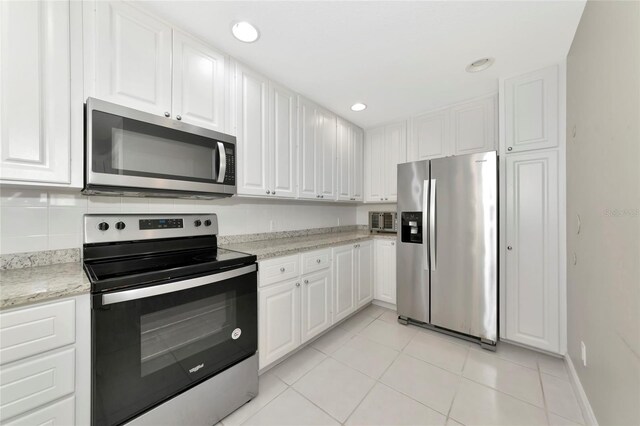kitchen with recessed lighting, white cabinetry, light stone counters, appliances with stainless steel finishes, and light tile patterned floors