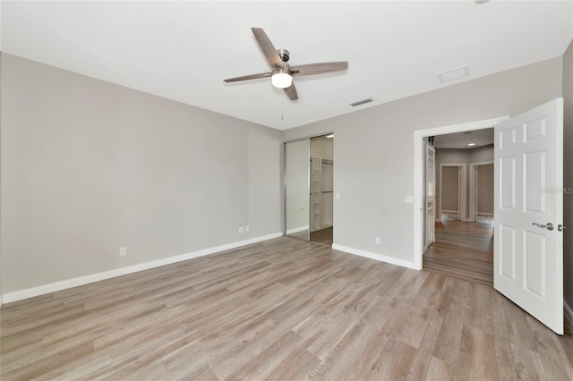 unfurnished bedroom featuring a ceiling fan, visible vents, baseboards, a closet, and light wood finished floors