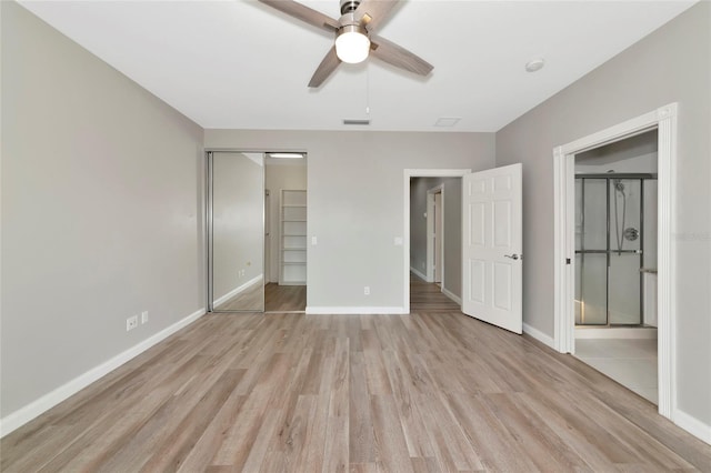 unfurnished bedroom with baseboards, light wood-style flooring, ensuite bath, and a closet