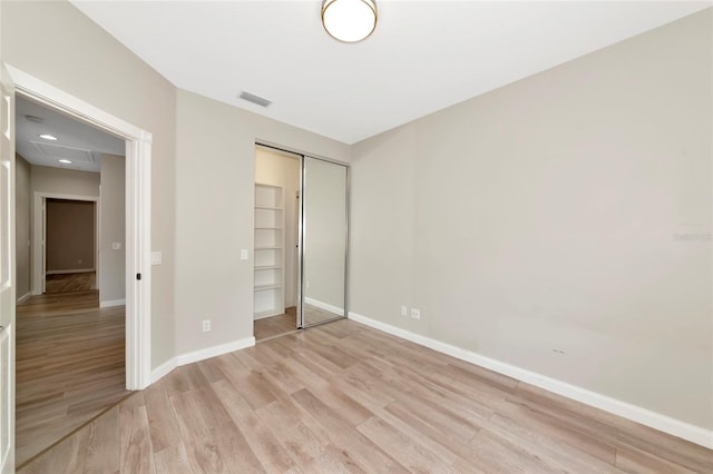 unfurnished bedroom with visible vents, light wood finished floors, baseboards, and a closet