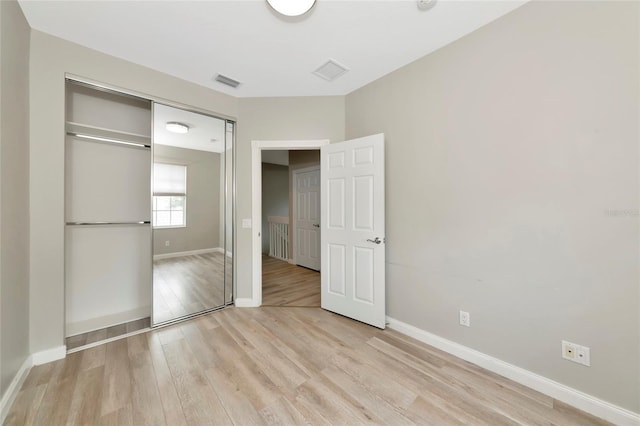 unfurnished bedroom with baseboards, visible vents, light wood finished floors, and a closet
